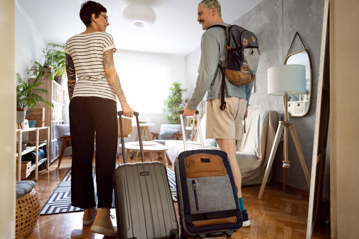 A young couple arriving at the accommodation with their suitcases.