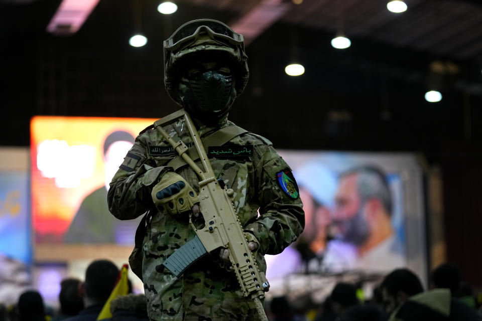 A boy wearing army-style fatigues gestures with a toy rifle during a ceremony to mark the anniversary of the death of Hezbollah leaders, in the southern suburbs of Beirut, Lebanon, Friday, Feb. 16, 2024. Hezbollah leader Sayyed Hassan Nasrallah vowed Friday to make Israel pay blood for the killing of civilians in southern Lebanon earlier this week. (AP Photo/Bilal Hussein)