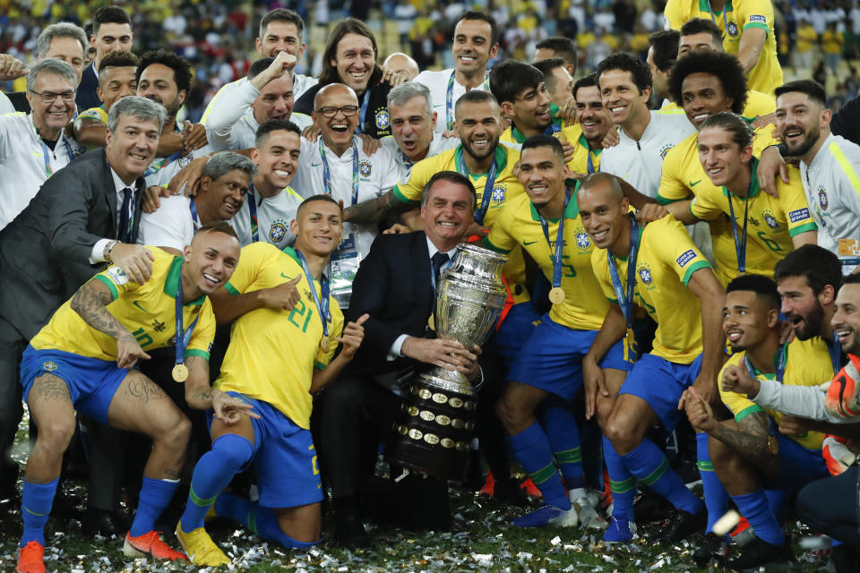 Brazil's President Jair Bolsonaro holds the trophy as he celebrates with Brazil players after they won 3-1 the final soccer match of the Copa America against Peru at the Maracana stadium in Rio de Janeiro, Brazil, Sunday, July 7, 2019. (AP Photo/Victor R. Caivano)