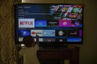 A child touches a TV screen displaying OTT streaming apps at his home in New Delhi, India, Thursday, Feb. 25, 2021. India has rolled out new regulations for social media companies and digital streaming websites to make them more accountable for the online content shared on their platforms. (AP Photo/Altaf Qadri)