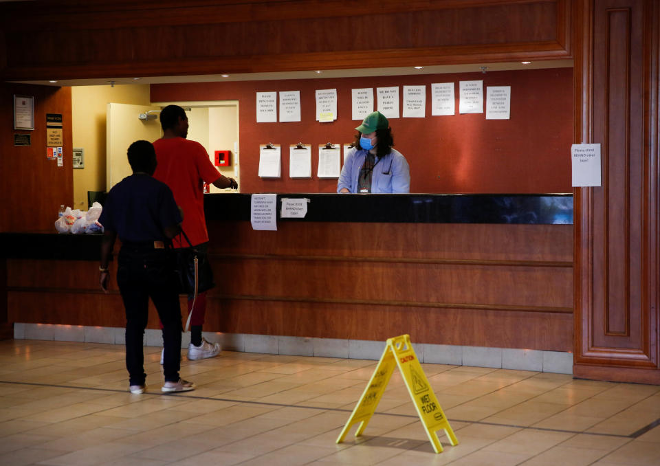 Clients talk with a staff member standing at the front desk at the Red Lion Hotel in Renton, Washington. (Photo: Lindsey Wasson/Reuters)