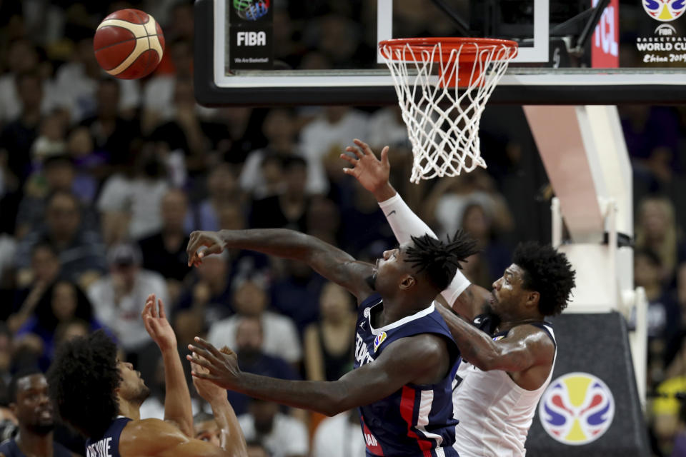 France's Mathias Lessort, center keeps the ball from United States' Marcus Smart at right during a quarterfinal match for the FIBA Basketball World Cup in Dongguan in southern China's Guangdong province on Wednesday, Sept. 11, 2019. France defeated United States 89-79. (AP Photo/Ng Han Guan)