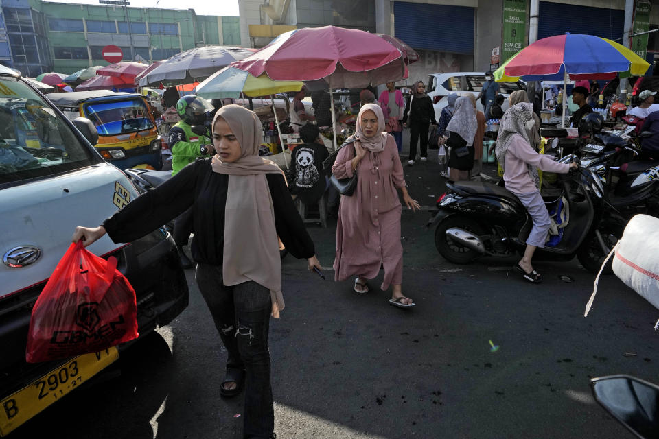 People cross a busy street at a market in Jakarta, Indonesia, Monday, Feb. 12, 2024. Indonesia, the world's third-largest democracy, will open its polls on Wednesday to nearly 205 million eligible voters in presidential and legislative elections, the fifth since Southeast Asia's largest economy began democratic reforms in 1998. (AP Photo/Achmad Ibrahim)