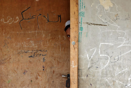 A boy from the Rohingya community peeps out from the door of a madrasa, or a religious school, at a camp on the outskirts of Jammu October 5, 2018. REUTERS/Mukesh Gupta