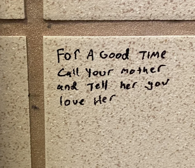 Text on a tiled wall reads, "For a good time, call your mother and tell her you love her."