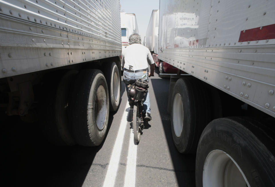 A man rides his bicycle past container trucks, that have come from all over the country to protest against the rising price of diesel, in front of Mexico City's San Lazaro legislative palace, February 24, 2009. REUTERS/Henry Romero(MEXICO)