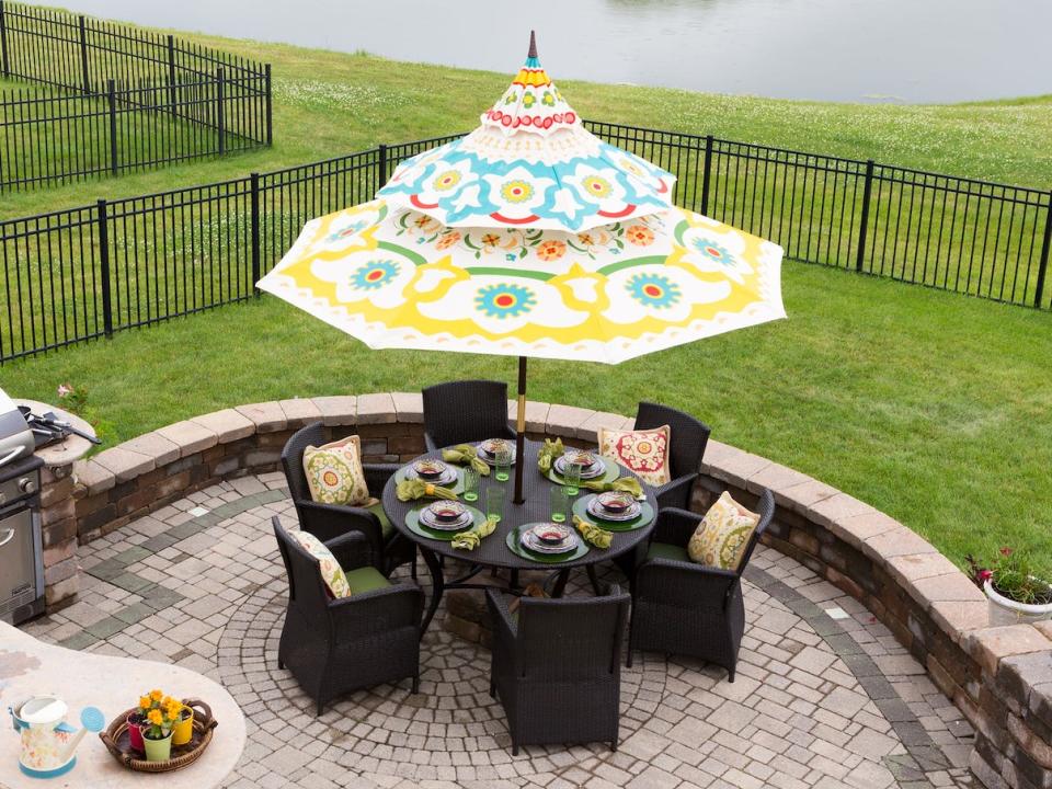 nice backyard patio with a sink, grill, table, and fun patterned umbrella