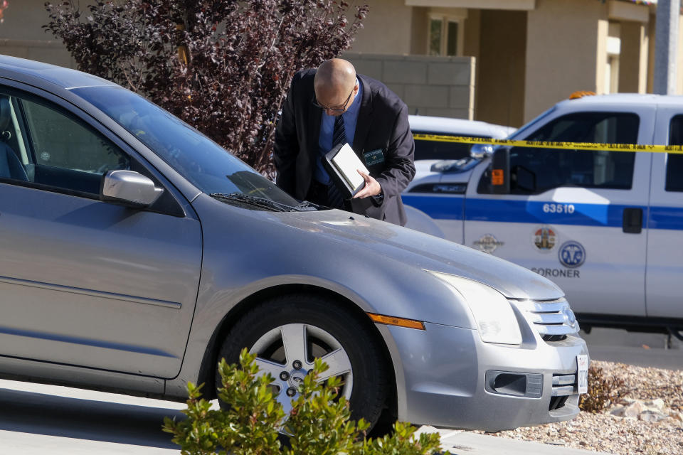 A law enforcement investigates a vehicle parked in the driveway of a home where five bodies were found in the city of Lancaster in the high desert Antelope Valley north of Los Angeles, Monday, Nov. 29, 2021. A Los Angeles County Sheriff's Department statement says deputies found a woman, a girl and three boys with gunshot wounds and paramedics pronounced them dead at the scene. The department says the children's father showed up at the Lancaster sheriff's station and was arrested on suspicion of five murders after being interviewed by detectives. (AP Photo/Ringo H.W. Chiu)