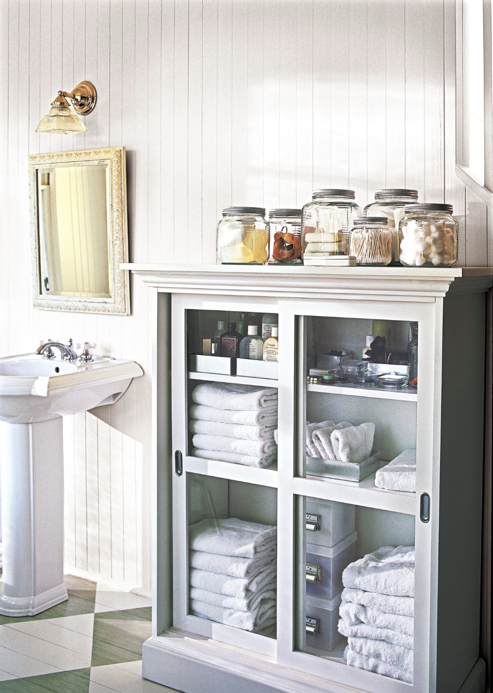 bathroom storage ideas, short cabinet with glass doors and folded towels and toiletries inside