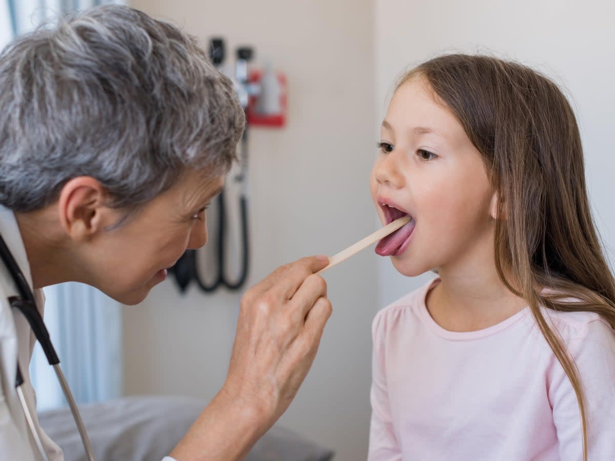 A GP inspecting a child’s tonsils  (Getty/iStock)
