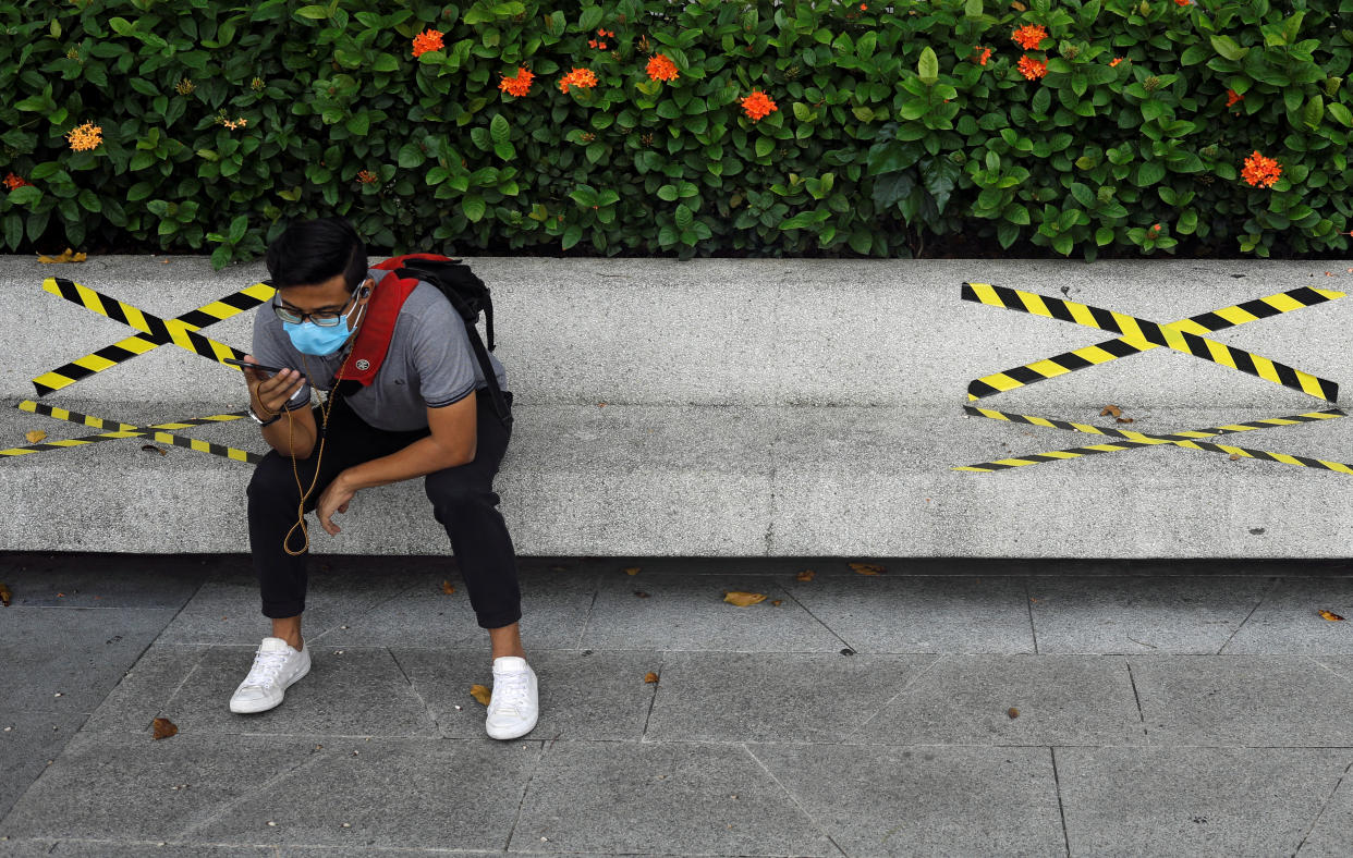 A man sits on a bench with distance markers along Marina Bay, amid the coronavirus disease (COVID-19) outbreak, in Singapore July 14, 2020. REUTERS/Edgar Su