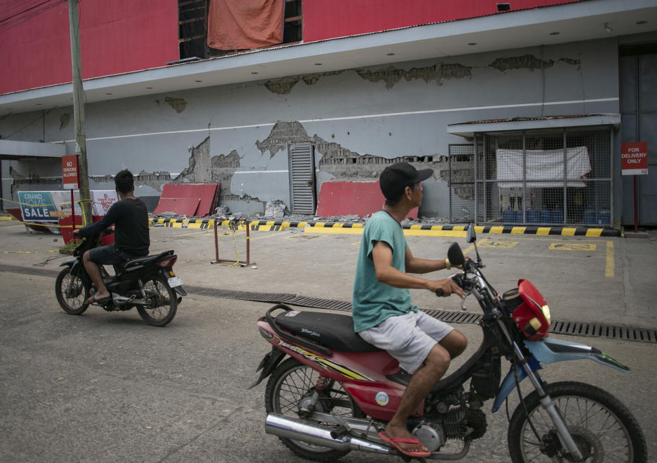 Men look at damages on a building a day after a strong quake struck in Digos, Davao del Sur province, southern Philippines Thursday, Oct. 17, 2019. A powerful and shallow earthquake hit several southern Philippine provinces Wednesday night injuring some people in collapsed houses and prompting thousands to scramble out of homes, shopping malls and a hospital in panic, officials and news reports said. (AP Photo)