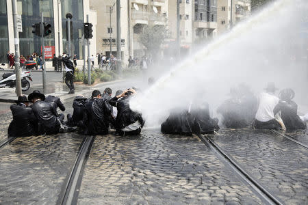 Ultra-Orthodox Jewish men are sprayed with a water canon by Israeli police as they block a road during a protest against the detention of one of their community members who evaded a military draft order, in Jerusalem August 2, 2018. REUTERS/Ammar Awad