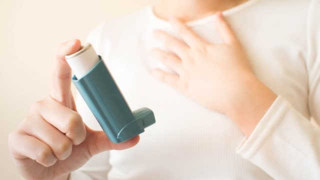 Person holding an asthma inhaler.