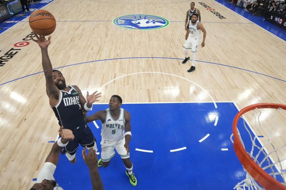 Dallas Mavericks guard Kyrie Irving shoots as Minnesota Timberwolves guard Anthony Edwards (5) defends during the first half of Game 1 of the NBA basketball Western Conference finals, Wednesday, May 22, 2024, in Minneapolis. (AP Photo/Abbie Parr)