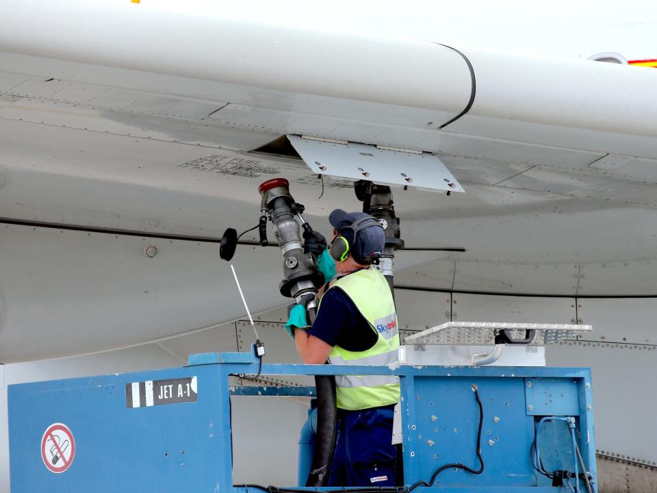 12 August 2022, Brandenburg, Schönefeld: A ground staff member refuels an Airbus A330-300 aircraft of the airline before the first flight of the Chinese airline Hainan from BER, at Berlin Brandenburg Airport.