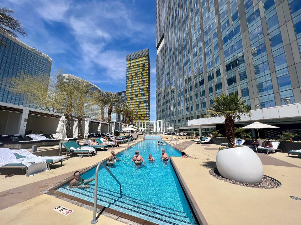 A narrow pool set against a tall building with loungers on each side.