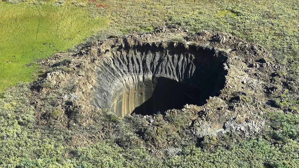  A deep crater in a grassy field. 