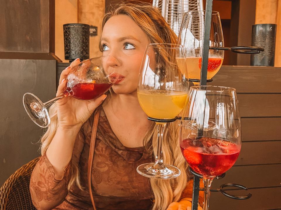 kayleigh drinking a glass of sangria with a flight of sangria in front of her at disney's coronado springs resort