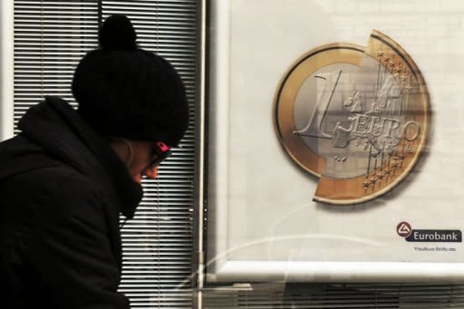 A woman walks by a sign showing a euro coin at a bank branch in Athens, January 2012. Greece's new prime minister and finance minister will for health reasons both miss a key EU summit where they were to launch efforts to renegotiate the terms of an unpopular austerity-centred bailout