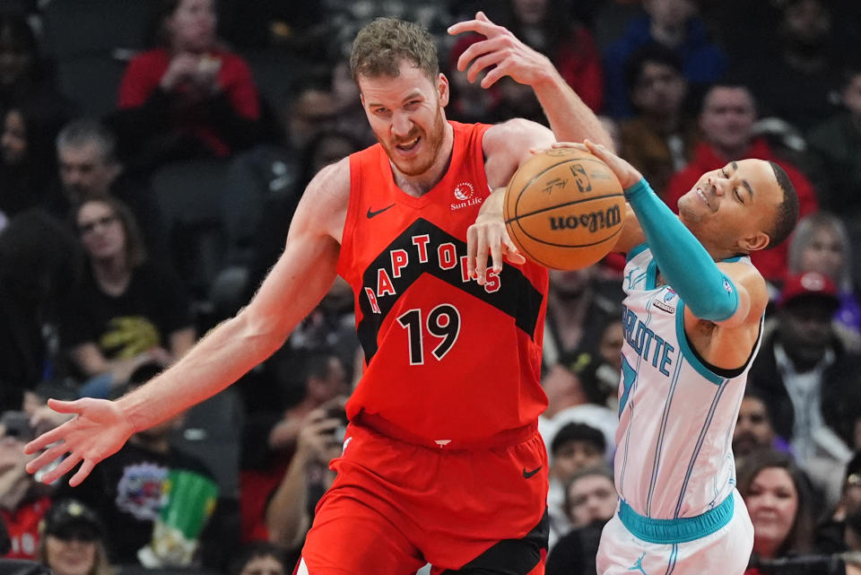 Toronto Raptors center Jakob Poeltl (19) and Charlotte Hornets guard Bryce McGowens, right, battle from control of the ball during first-half NBA basketball game action in Toronto, Sunday, March 3, 2024. (Frank Gunn/The Canadian Press via AP)
