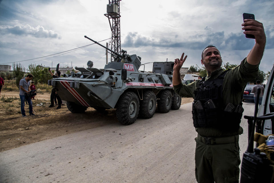 A member of Asayish, or the Internal Security Forces, makes a selfie by an Russian military vehicle during a patrol near Syrian and Turkish border in north Syria, Friday. Oct. 25, 2019. (AP Photo/Baderkhan Ahmad)