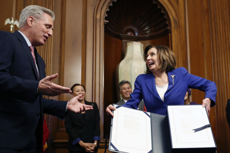 House Speaker Nancy Pelosi of Calif., accompanied by House Minority Leader Kevin McCarthy of Calif., and other legislators, participate in a bill enrollment ceremony for the Coronavirus Aid, Relief, and Economic Security (CARES) Act, after it passed in the House, on Capitol Hill, Friday, March 27, 2020 in Washington. The $2.2 trillion package will head to Trump's desk for his signature. (AP Photo/Andrew Harnik)