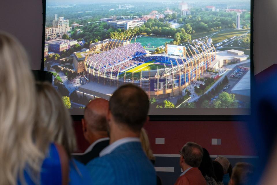 Invited guests to Tuesday's University of Kansas Gateway District reveal watch a video showing motion renderings of a reimagined David Booth Kansas Memorial Stadium along with other amenities to create the district surrounding it.