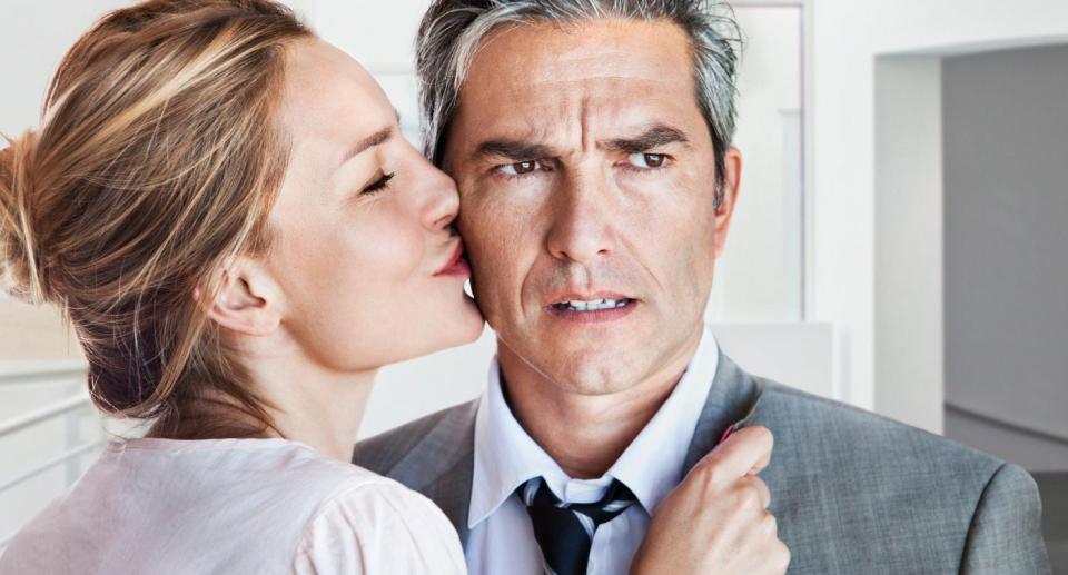 Cheating in the workplace: Woman kissing concerned man in a business suit 