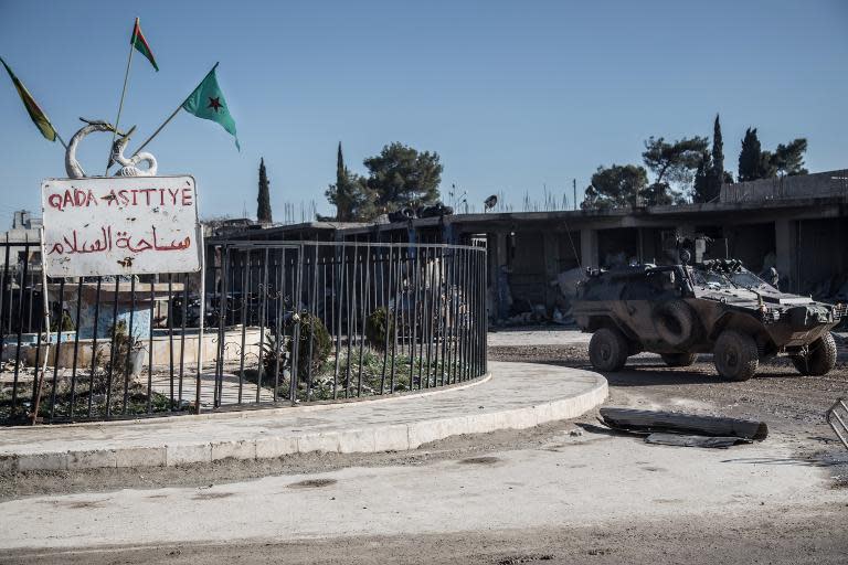 Turkish army vehicles drive in a street of the Syrian town of Kobane, (aka Ain al-Arab) on February 22, 2015, during an operation to relieve the garrison guarding the Suleyman Shah mausoleum in northern Syria