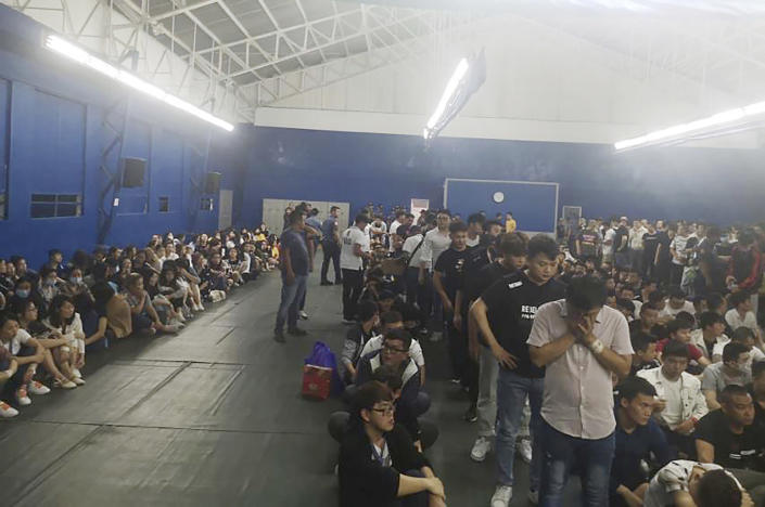 In this Oct. 9, 2019, photo provided by Philippine Bureau of Immigration, foreign nationals, mostly Chinese are housed in a gymnasium following a raid at their company premises in Manila, Philippines. Philippine police and immigration authorities said they have arrested more than 500 illegally working foreigners, mostly Chinese involved in telecommunications and investment scams, in one of the biggest such mass arrests this year. (Philippine Bureau of Immigration Via AP)