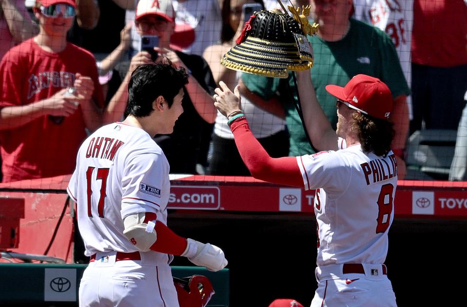 Los Angeles Angels outfielder Brett Phillips puts a samurai hat on teammate Shohei Ohtani to celebrate his home run on April 9, 2023, in Anaheim.