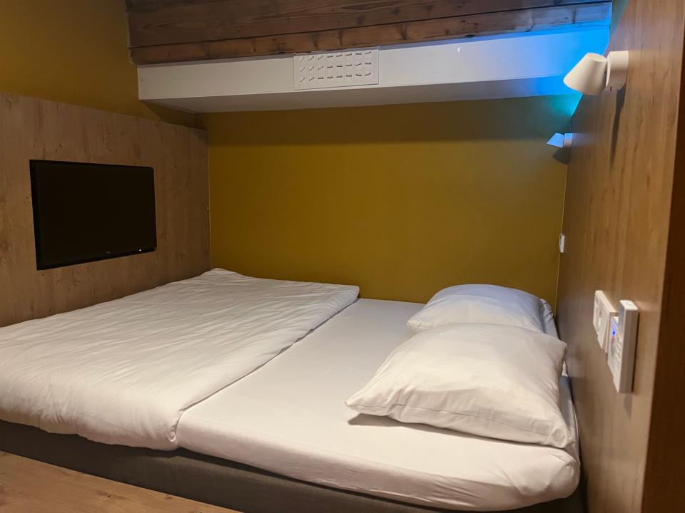 A hotel room with a small bed and yellow walls