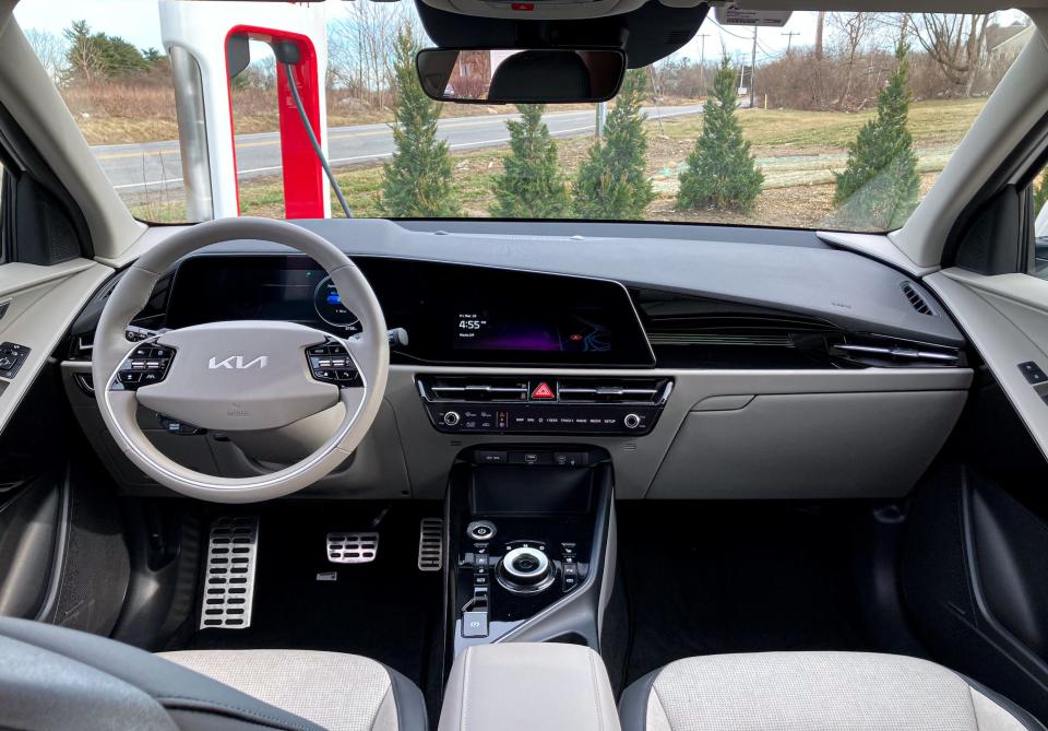 The interior of the Kia Niro EV electric SUV taken facing the windshield, featuring gray steering wheel and seats, darker accents,