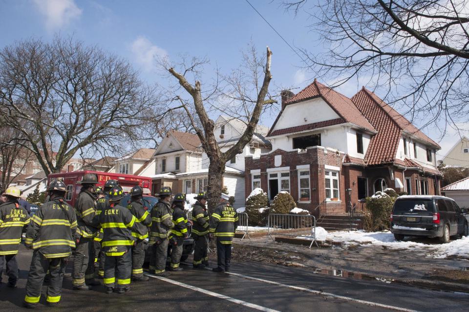 Firefighters stand outside a home hours after it caught fire in the Midwood neighborhood of Brooklyn, New York