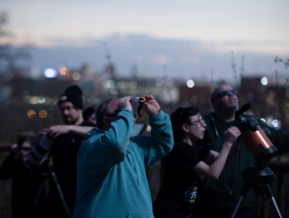 Dan Kovac of Lake Milton looks up during the eclipse Monday with the city of Akron behind him at the Akron Zoo.