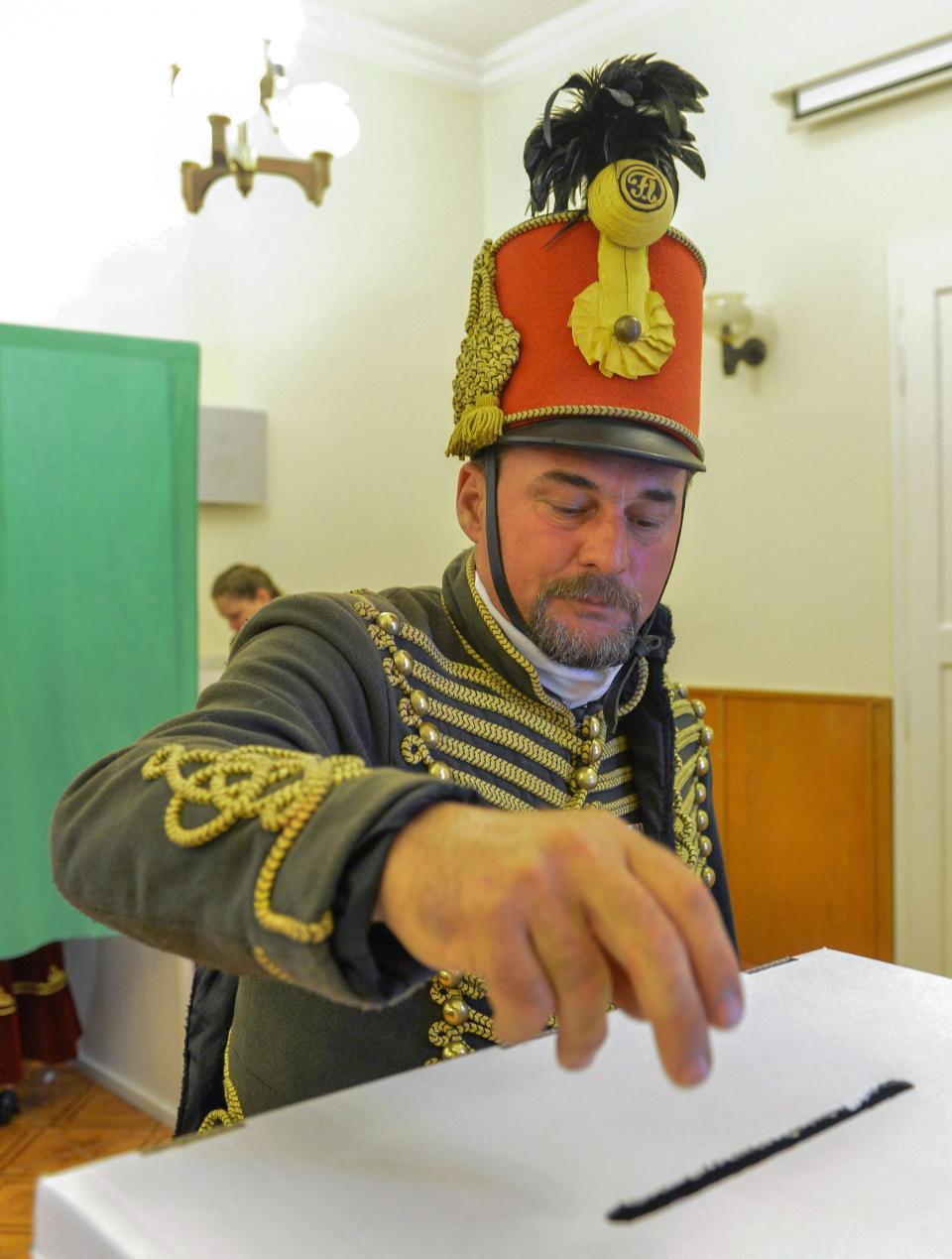 A traditionalist (no name available) dressed in a hussars’ uniform casts his ballot at a polling station in Isaszeg 35 kms northeast of Budapest during the parliamentary elections in Hungary, Sunday April 6, 2014. Hungary's governing party is tipped to win parliamentary elections Sunday, while a far-right party is expected to make further gains, according to polls. Prime Minister Viktor Orban's Fidesz party and its small ally, the Christian Democrats, are expected to win easily and they may even retain the two-thirds majority in the legislature gained in 2010 which allowed them to pass a new constitution, adopt unconventional economic policies, centralize power and grow the state's influence at the expense of the private sector.(AP Photo/MTI,Tibor Illyes)