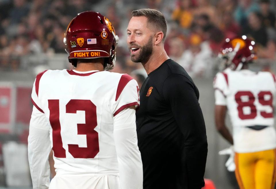 The former Arizona Cardinals head coach and now USC Trojans assistant coach Kliff Kingsbury talks to quarterback Caleb Williams (13) during the pregame warmup before playing the Arizona State Sun Devils at Mountain America Stadium in Tempe on Sept. 23, 2023.