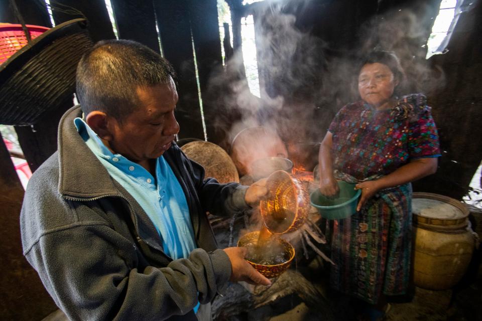 Maria Elvira Ramos serves her husband, Francisco Sical, coffee in a traditional Mayan bowl in early March. Her outdoor kitchen is flanked with timber. Sical promised her a kitchen of cement block with money he would make working in the USA, a dream he gave up in summer 2019.