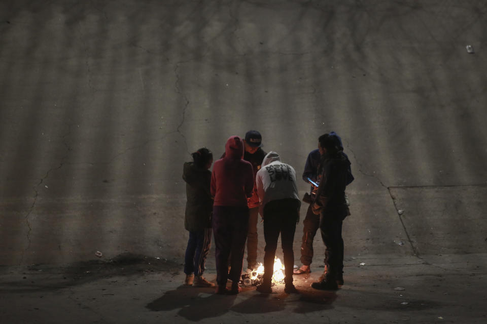 Migrants gather near a camp fire near the U.S.-Mexico border as seen from Ciudad Juarez, Mexico, Tuesday, Dec. 20, 2022. The U.S. Supreme Court issued a temporary order to keep pandemic-era limits on asylum-seekers in place, though it could be brief, as conservative-leaning states push to maintain a measure that allows officials to expel many but not all asylum-seekers. (AP Photo/Christian Chavez)