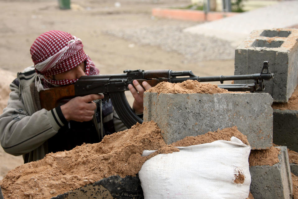 In this Sunday, Jan. 5, 2014 picture, a gunman aims his weapon during clashes with Iraqi security forces in Fallujah, Iraq. Clashes continued late Sunday and early morning Monday between al-Qaida and Iraqi troops on the main highway that links the capital, Baghdad, to neighboring Syria and Jordan. Al-Qaida fighters and allied tribes are still controlling the center of the city where they are deployed in streets and around government buildings. A burst of strength by al-Qaida that is chipping away at the remains of Mideast stability now confronts President Barack Obama, testing his hands-off approach to conflicts in Iraq and Syria at the same time he pushes to keep thousands of U.S. forces in Afghanistan. (AP Photo)