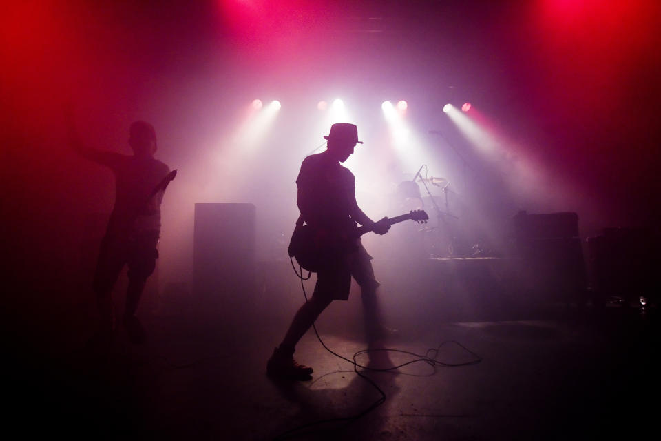 A shadowy man playing guitar onstage