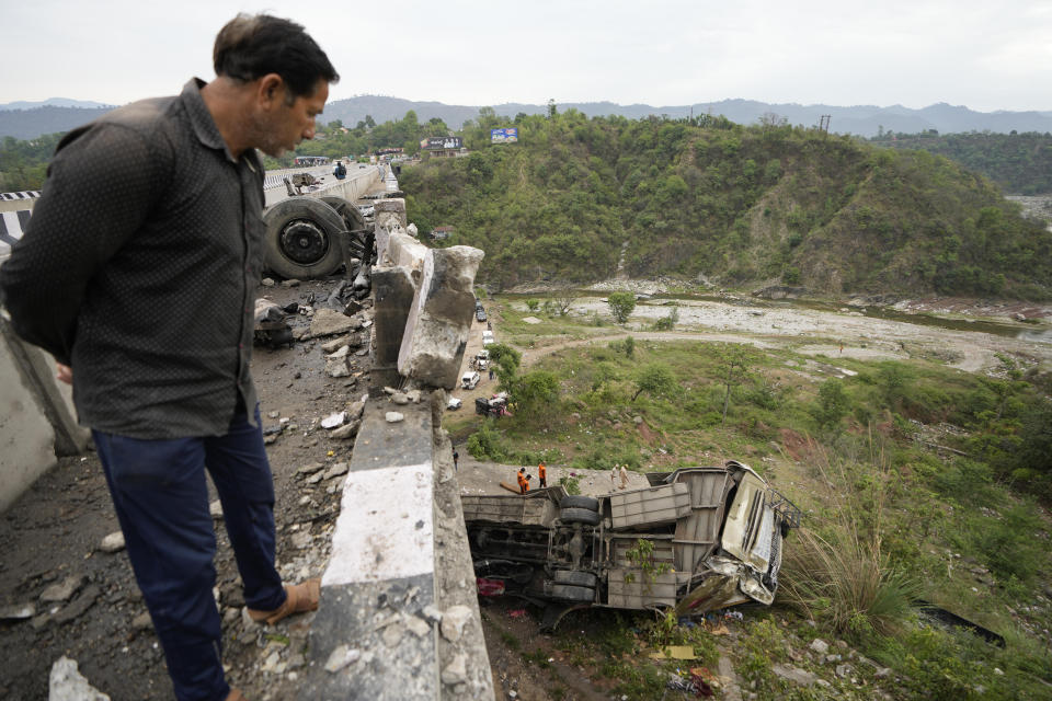 A man looks at the wreckage after a bus carrying Hindu pilgrims to a shrine skid off a highway bridge into a Himalayan gorge near Jammu, India, Tuesday, May 30, 2023. (AP Photo/Channi Anand)