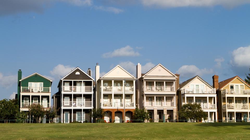 Upscale townhomes for the wealthy built on a grass hill in a row against a cloudy blue sky in Memphis, Tennessee.