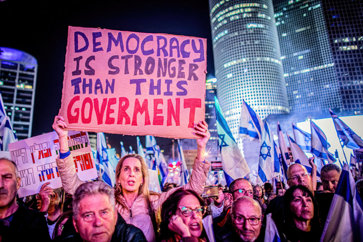 Israeli protesters hold placards reading: Democracy is stronger than this government.