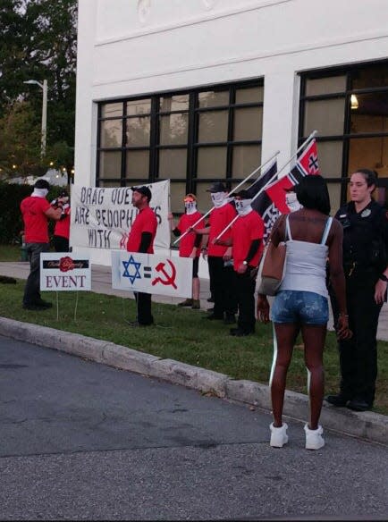 A Lakeland Police Department officer is seen standing near a group of men displaying Nazi symbols Saturday evening as they protest outside A Celebration of the Arts, an event featuring drag performances at ART/Ifacts Studio.