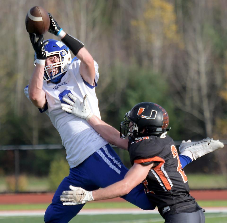 Lunenburg's Ben Bartow catches a pass for a first down as Uxbridge's Zachary Oliviera defends.