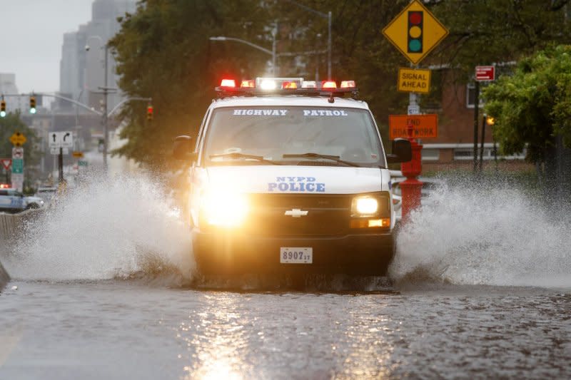 An NYPD vehicle crosses a flooded road. Photo by John Angelillo/UPI