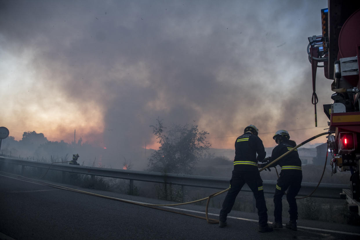 GRANADA, SPAIN - JULY 12: Two firefighters prepare the rubber to put out the fire along the Viznar road on July 12, 2021 in Granada, Spain. A fire in an area between Granada, Jun and Viznar has forced the activation of emergency level 1, due to high temperatures and the force of the wind. Scientists have warned that climate change will cause huge forest fires, even with just a 0.5 degree rise in temperatures. (Photo by Carlos Gil Andreu/Getty Images)