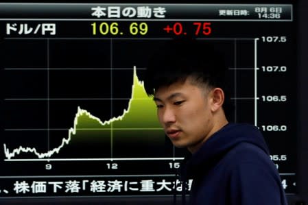 FILE PHOTO: An employee of a foreign currency company walks past in front of a graph showing recent movements of the exchange rates between the Japanese yen and the U.S. dollar at a dealing room in Tokyo